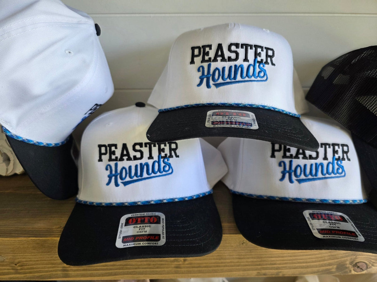 Three white and black snapback trucker hats with 'PEASTER Hounds' embroidered on the front, displayed on a wooden shelf form Josie Threads